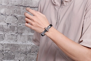 Detailed view of men's black braided leather bracelet with silver steel cross buckle