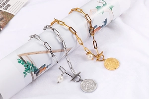 Détail de colliers trombones en or et argent avec pendentifs perle et médaille