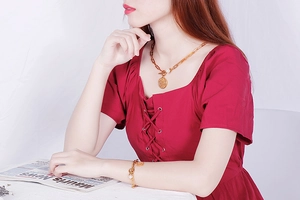 Détail d'un ensemble collier et bracelet élégant en acier titane doré porté par un mannequin
