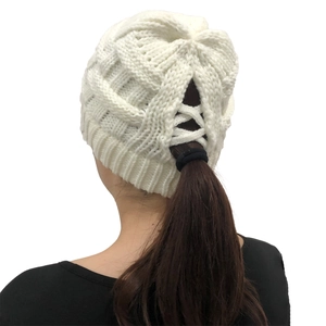 Detail of white cable knit ponytail beanie with criss-cross elastic opening at the back