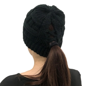 Detail of black cable knit ponytail beanie featuring a cross back opening for hair