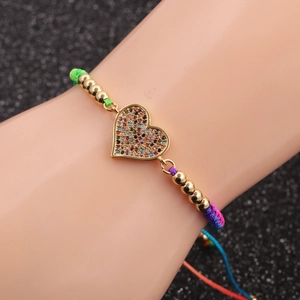 Micro-inlaid heart charm bracelet with gold beads and colorful woven cord on wrist