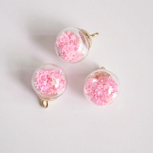 Detailed view of 16mm glass globe charms with pink star glitter and gold metal rings