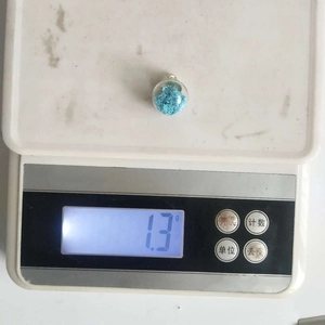 Detailed view of a 16mm blue star-filled glass ball pendant weighing 1.3g on a scale