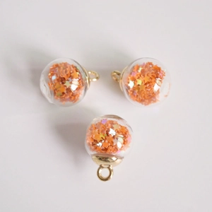 Macro detail of 16mm orange glass balls with star sequins and golden metal loops