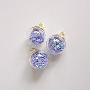Detailed view of three purple star-filled glass ball charms with gold metal loops