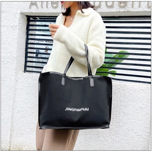 Chic black tote bag with white text print worn on shoulder for stylish daily commute