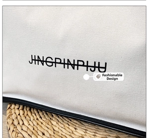 Close-up of white canvas tote bag with black leather piping and minimalist text logo