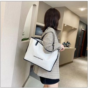 Close-up of white tote bag with black trim and JINGPINPIJU text decoration