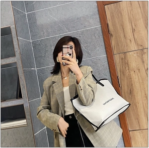 Mirror selfie showing the large white tote bag with black trim and minimalist lettering