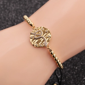 Adjustable black rope bracelet with gold snake coin charm and sparkling white zircon accents