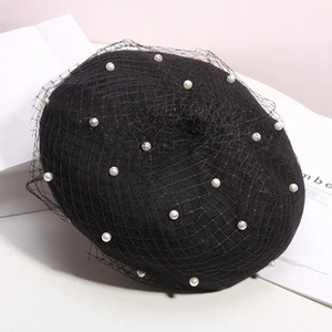 Detail of black knitted beret featuring delicate mesh overlay and white pearl accents