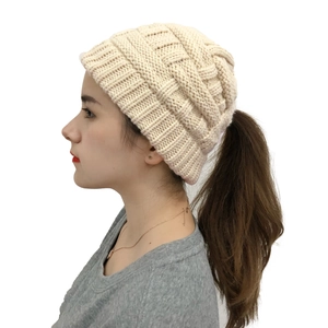 Detail view of cream-colored knit beanie with a ponytail hole design for women