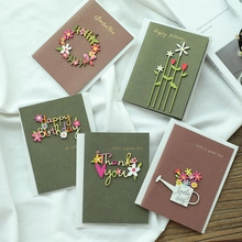 Flat lay of colorful paper greeting cards with 3D floral designs on white fabric background
