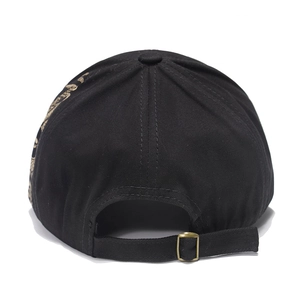 Detail view of adjustable bronze buckle and golden embroidery on black cotton baseball cap
