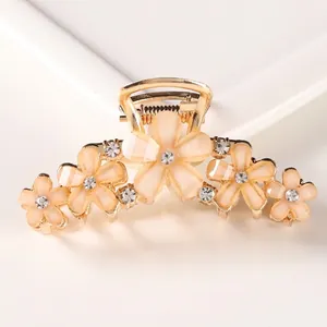 Detail of floral hair claw clip with peach resin petals and gold alloy rhinestone inlay