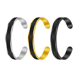 Close-up of C-shaped metal bracelets in silver, gold, and black with textured inlay