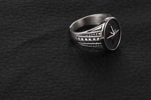 Macro shot of silver titanium steel signet ring with star compass engraving and side ridges