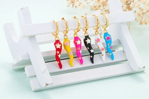 Detail of colorful chili pendant earrings with star patterns on a wooden display stand
