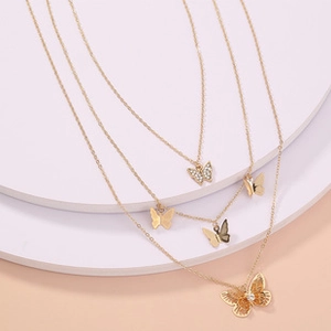 Macro detail of triple-layer gold butterfly necklace with zircon stones on a white stand