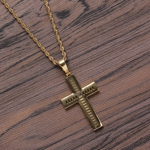 Detailed close-up of gold cross pendant with central zircon on dark wood surface