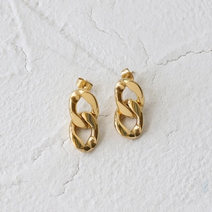Macro detail of chunky 18K gold plated chain link earrings on white stone background