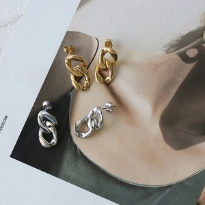 Minimalist thick chain link stud earrings in 18K gold and silver tones on magazine