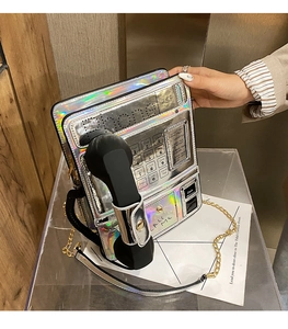 Bolso bandolera plateado holográfico con forma de teléfono público y cadena dorada.