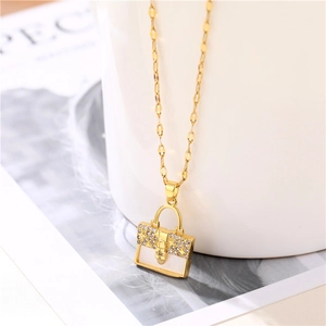 Elegant gold necklace featuring a white enamel handbag pendant with crystals on a chain
