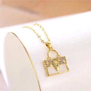 Elegant gold necklace with a crystal-encrusted handbag pendant on a white background