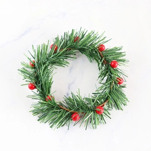 Artificial Christmas wreath with red berries and pine needles on white marble background