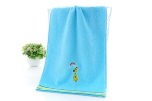 Detail eines hellblauen Baumwollhandtuchs mit Giraffenstickerei an weißem Aufhänger