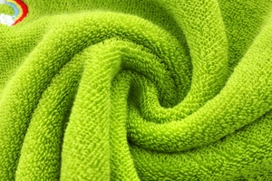 Macro detail of soft green cotton loops with a colorful rainbow embroidery on a kids towel