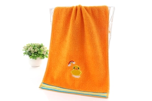 Detail eines weichen orangefarbenen Baumwollhandtuchs mit Entenstickerei und Streifen