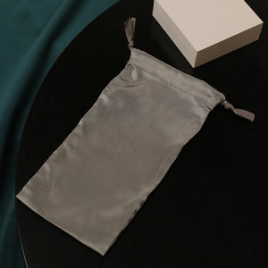 Elegant grey silk drawstring storage bag with premium off-white gift box on dark background