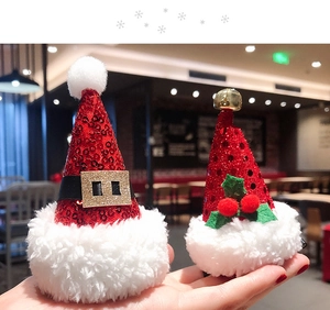 Detail of Christmas hat hair clips with red sequins, holly leaves, and small golden bells