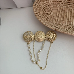 Detailed view of Baroque gold brooch with heraldic engraving and white pearl droplets