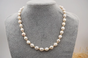 Detailed view of baroque freshwater pearl necklace with gold beads on a neck bust display