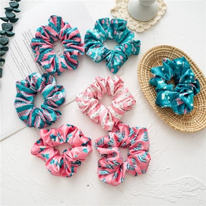 Detailed set of seven velvet scrunchies in pink and green colors on a white texture
