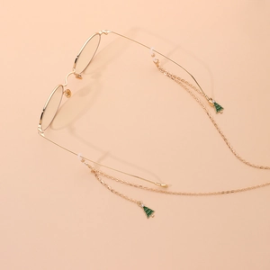 Golden eyewear chain with green enamel Christmas tree charm on a minimalist background