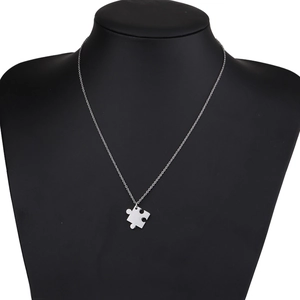 Gros plan d'un collier avec pendentif puzzle argenté sur un mannequin noir