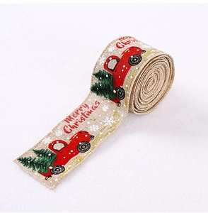 Close-up of linen Christmas ribbon featuring red truck and green tree prints