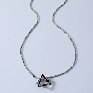 Detail of a geometric 3D triangle pendant on a silver box chain necklace