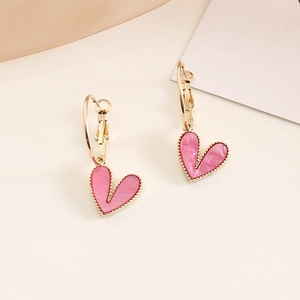 Detail of pink heart-shaped earrings with gold bead edges and lustrous texture