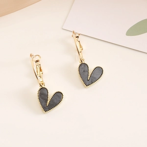 Detail of heart drop earrings with gold frames and grey marble resin on a beige background