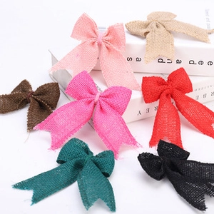 Close-up of 7 colorful faux burlap ribbon bows for DIY Christmas decorations on white surface