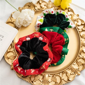 Three-piece set of Christmas velvet scrunchies with festive ribbon details in a gift tray
