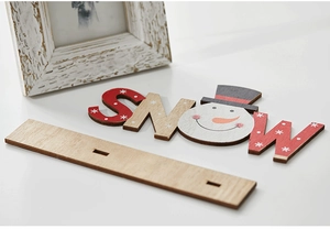 Close-up of wooden 'SNOW' Christmas tabletop ornament with hand-painted snowman detail