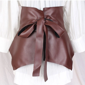 Close-up of brown leather corset belt featuring ruffled hem and front bow-knot lace-up detail