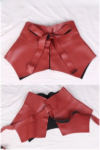 Detail of red PU leather ruffled corset belt featuring decorative lace-up bow design